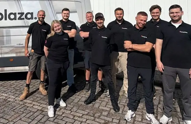 Het team van Bouwplaza staat samen naast de bedrijfsbus